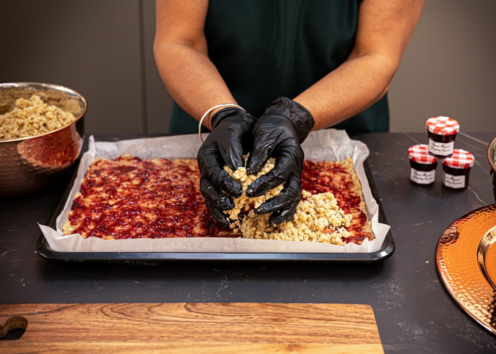 Raspberry conserve being layered into a fresh batch of flapjack mix